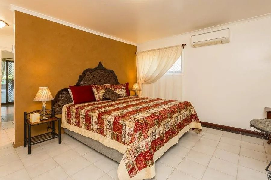 Bedroom With a Decorative Headboard, Red and Gold Bedding, and a Gold Accent Wall — Villa Lamor in Balberra, QLD
