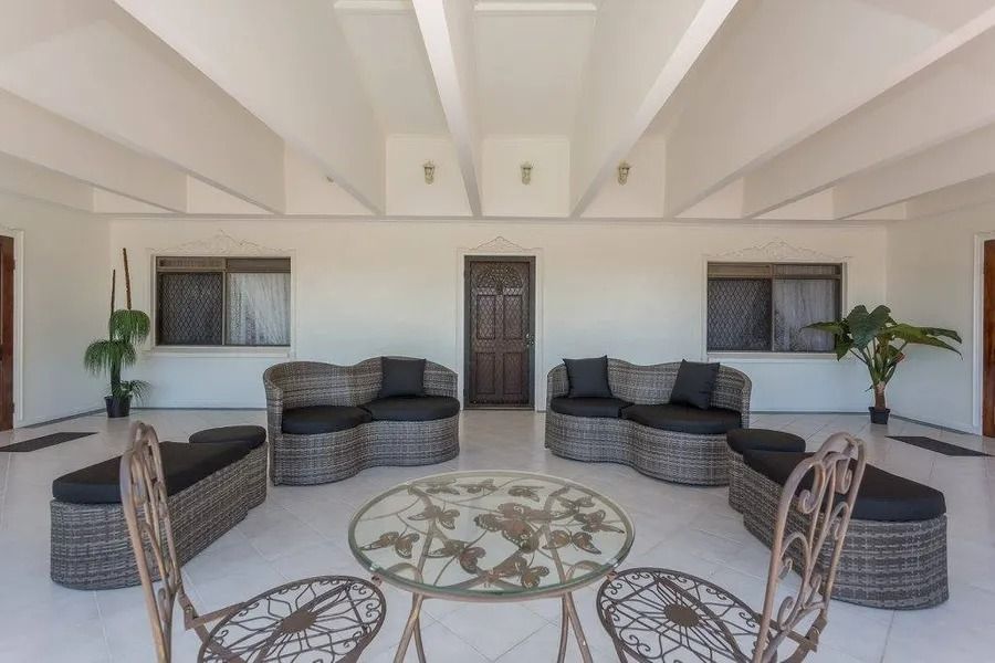 Covered Outdoor Seating Area With Wicker Furniture and a Glass-topped Table — Villa Lamor in Balberra, QLD