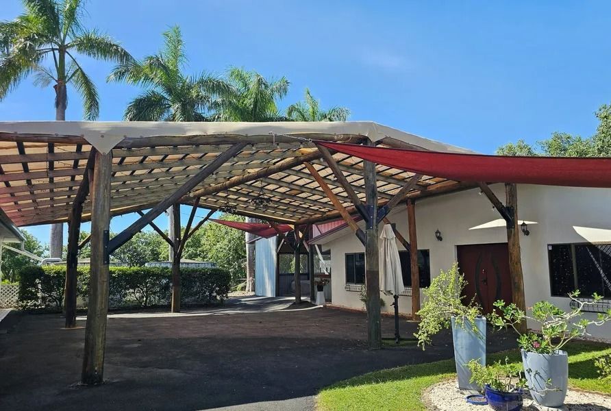 Carport With Wooden Supports and Canvas Roof Over Driveway — Villa Lamor in Balberra, QLD