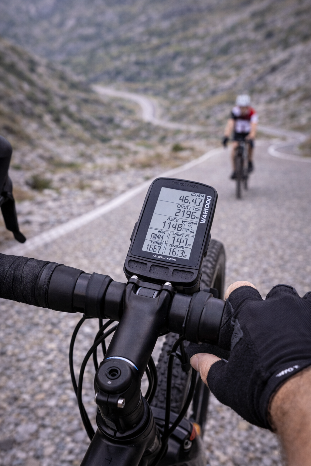 Prospettiva di un ciclista in bicicletta, con manubrio esposto, che segue un altro ciclista su una strada di montagna tortuosa.