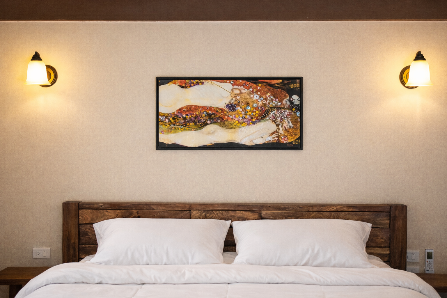 A bedroom with a bed, two gray pillows, one patterned pillow, two round wall art pieces, and a lamp on a small side table.
