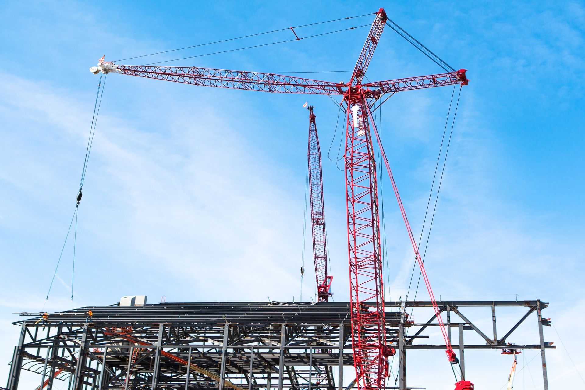 Un cantiere con gru e un cielo azzurro sullo sfondo.