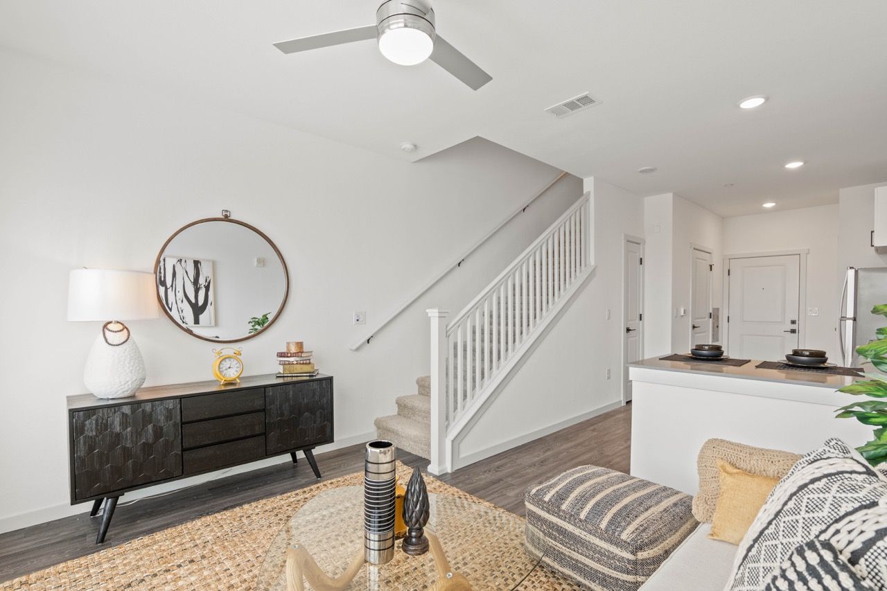 Open-concept living area in a modern apartment with a staircase, console table, and kitchen counter.