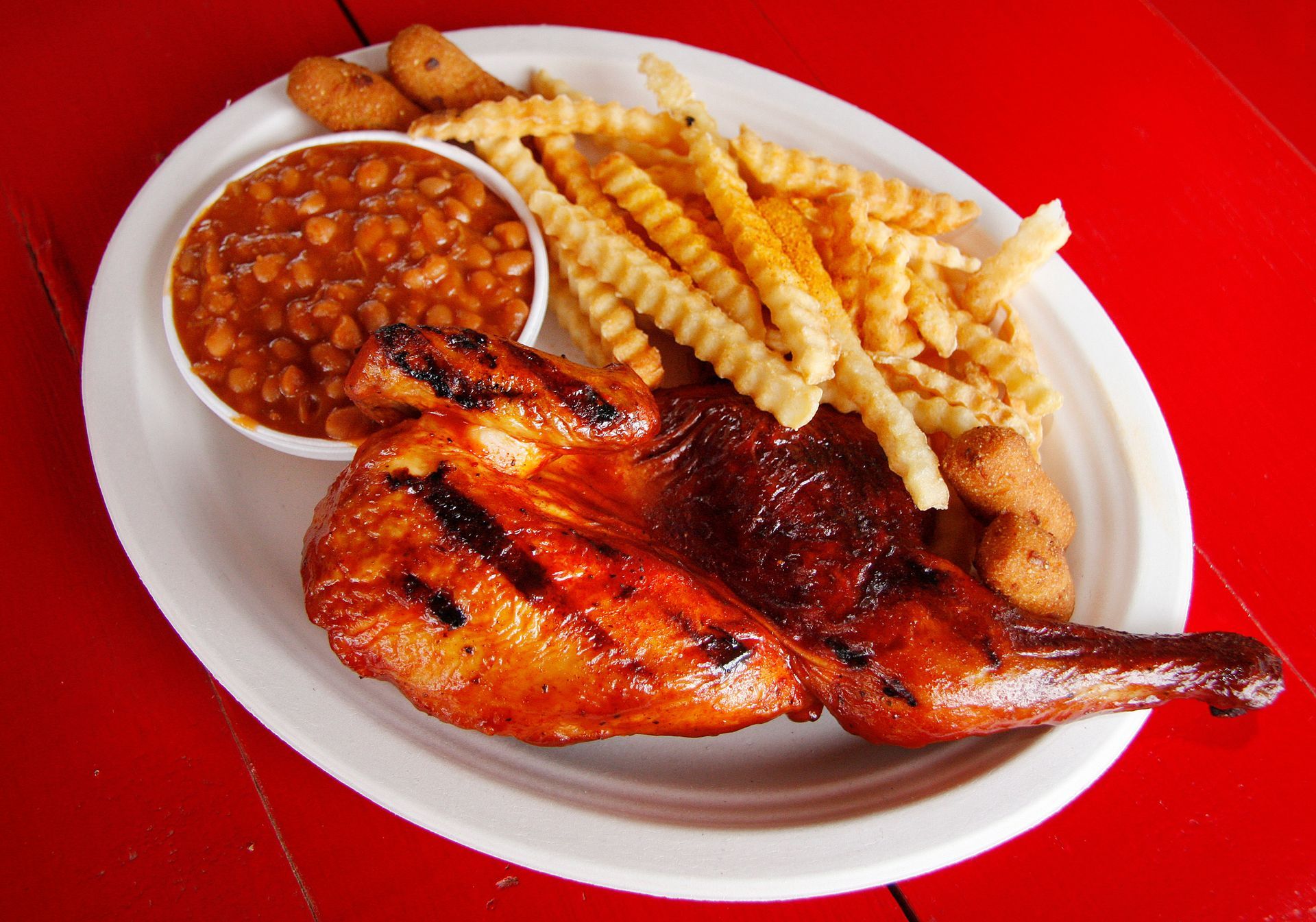 a white plate topped with grilled chicken french fries and baked beans