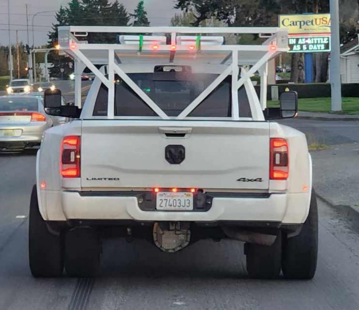A white truck is driving down a street with a carpet usa sign in the background