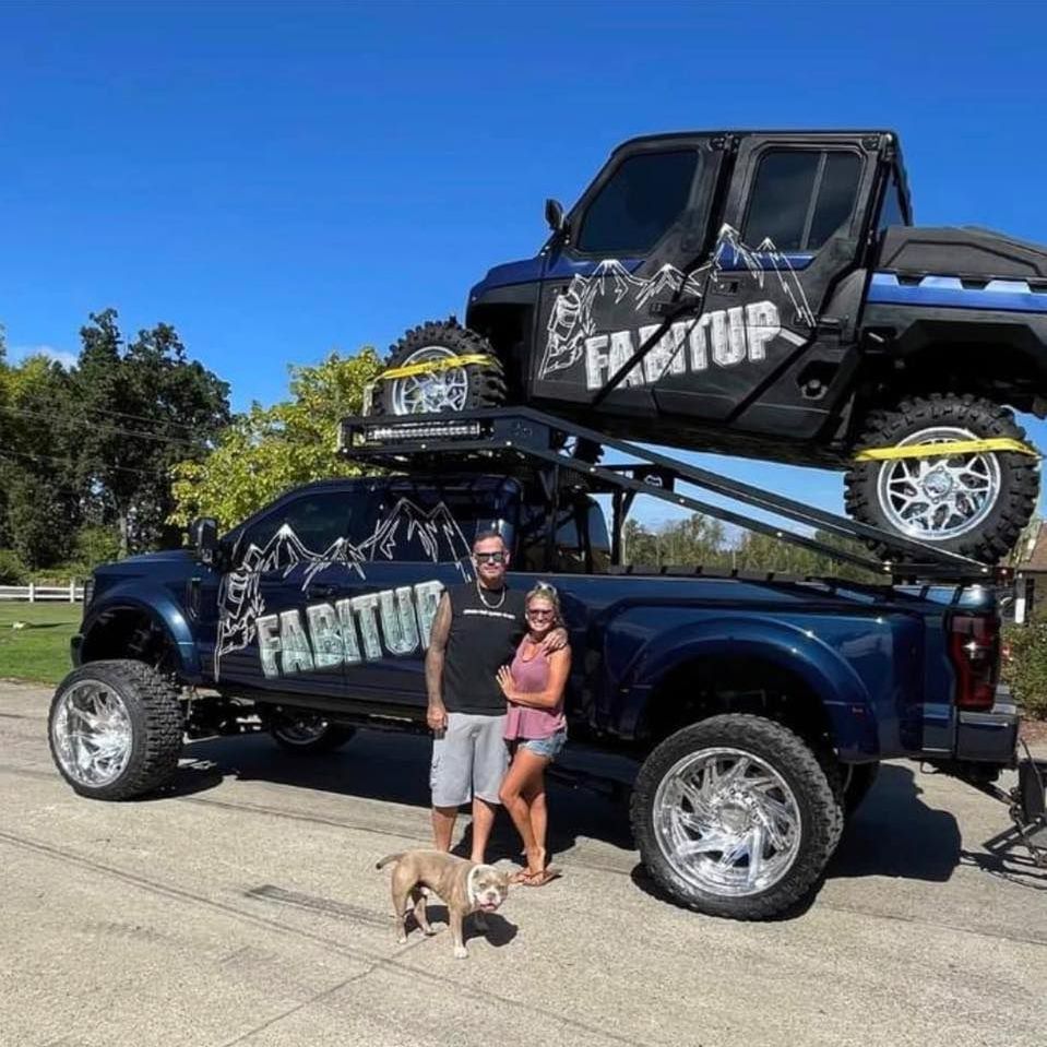 A man and woman standing in front of a truck that says fabritur