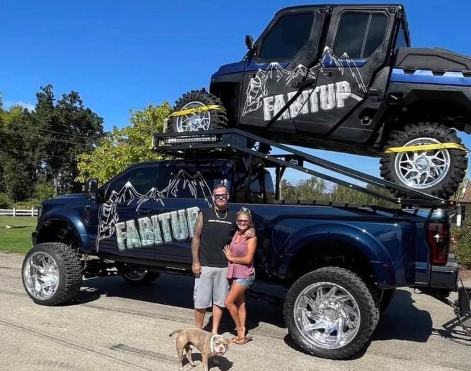 A man and woman standing in front of a truck that says fabitup