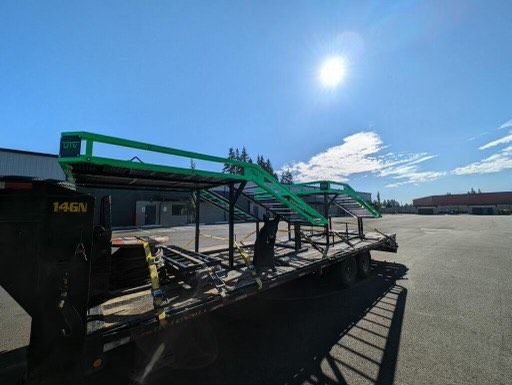 A trailer with a green ramp on top of it is parked in a parking lot.