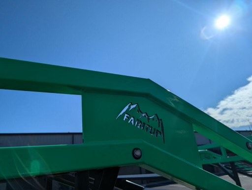 A green forklift is parked in front of a building on a sunny day.