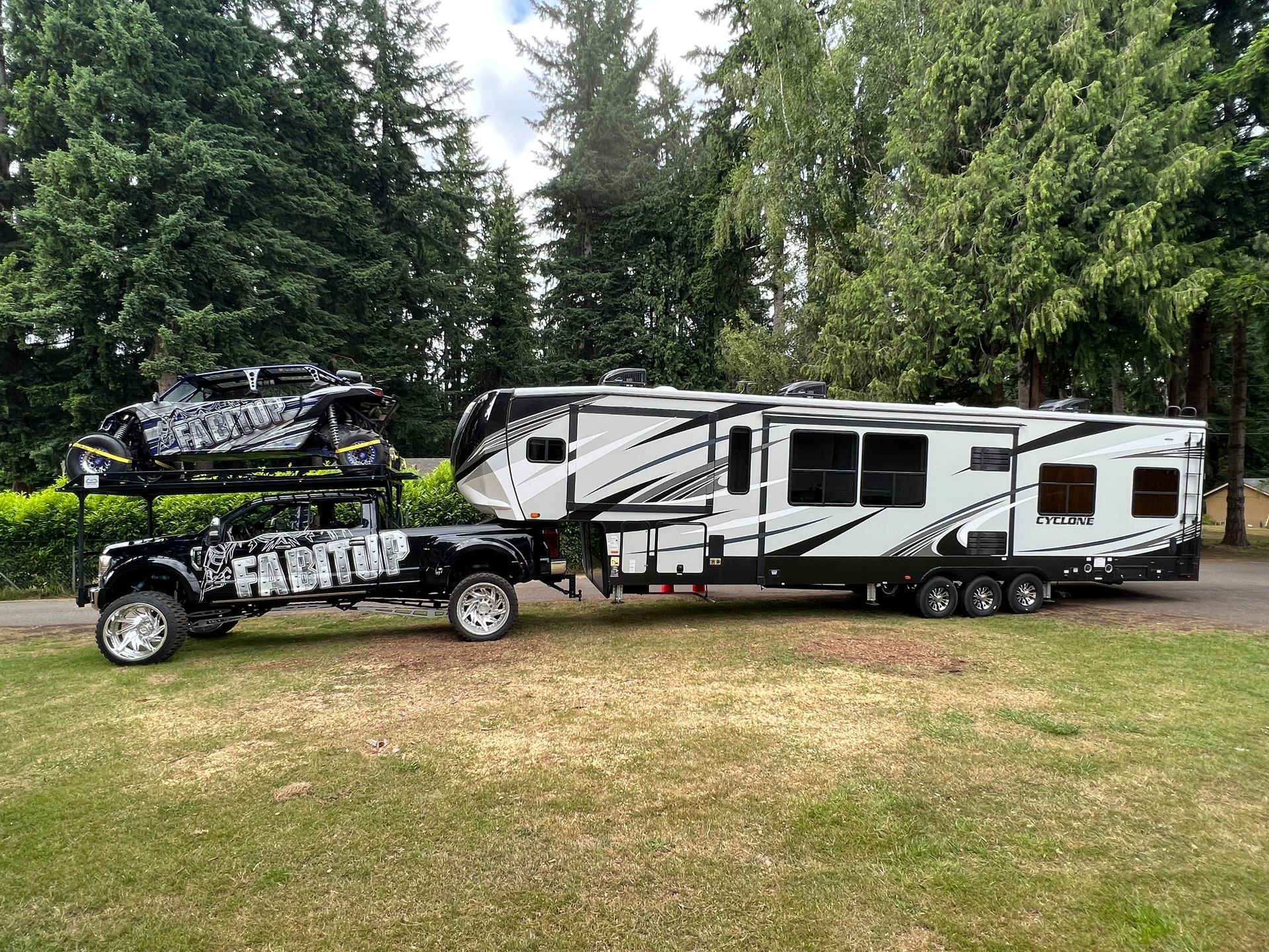 A truck is towing a trailer with a snowmobile on top of it.