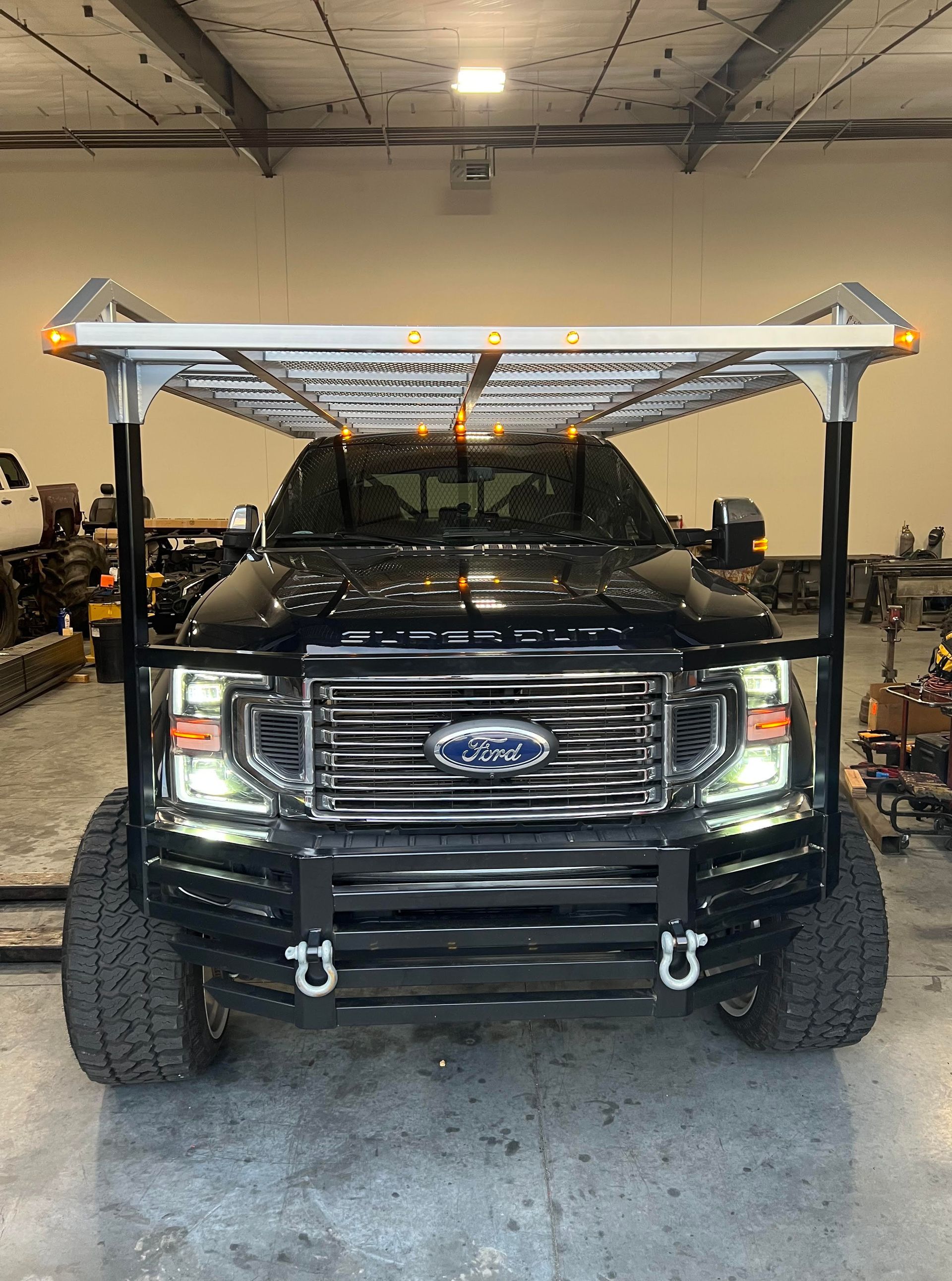 A black ford truck is parked in a garage with a ladder on top of it.