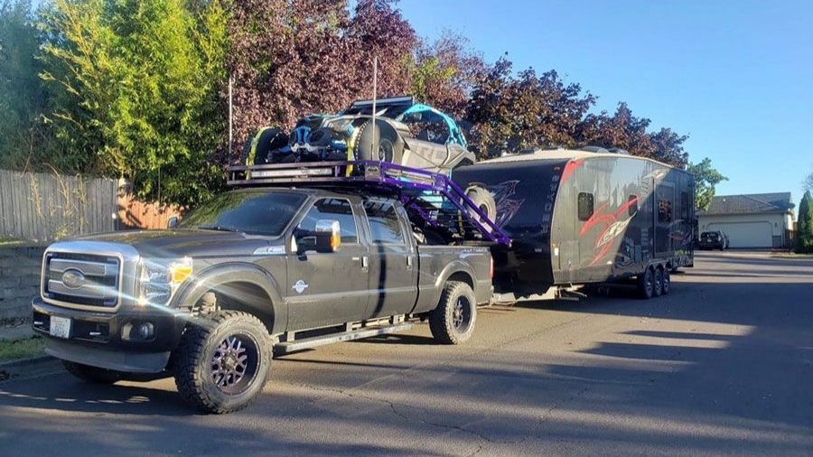 A truck is towing a trailer with a car on top of it.