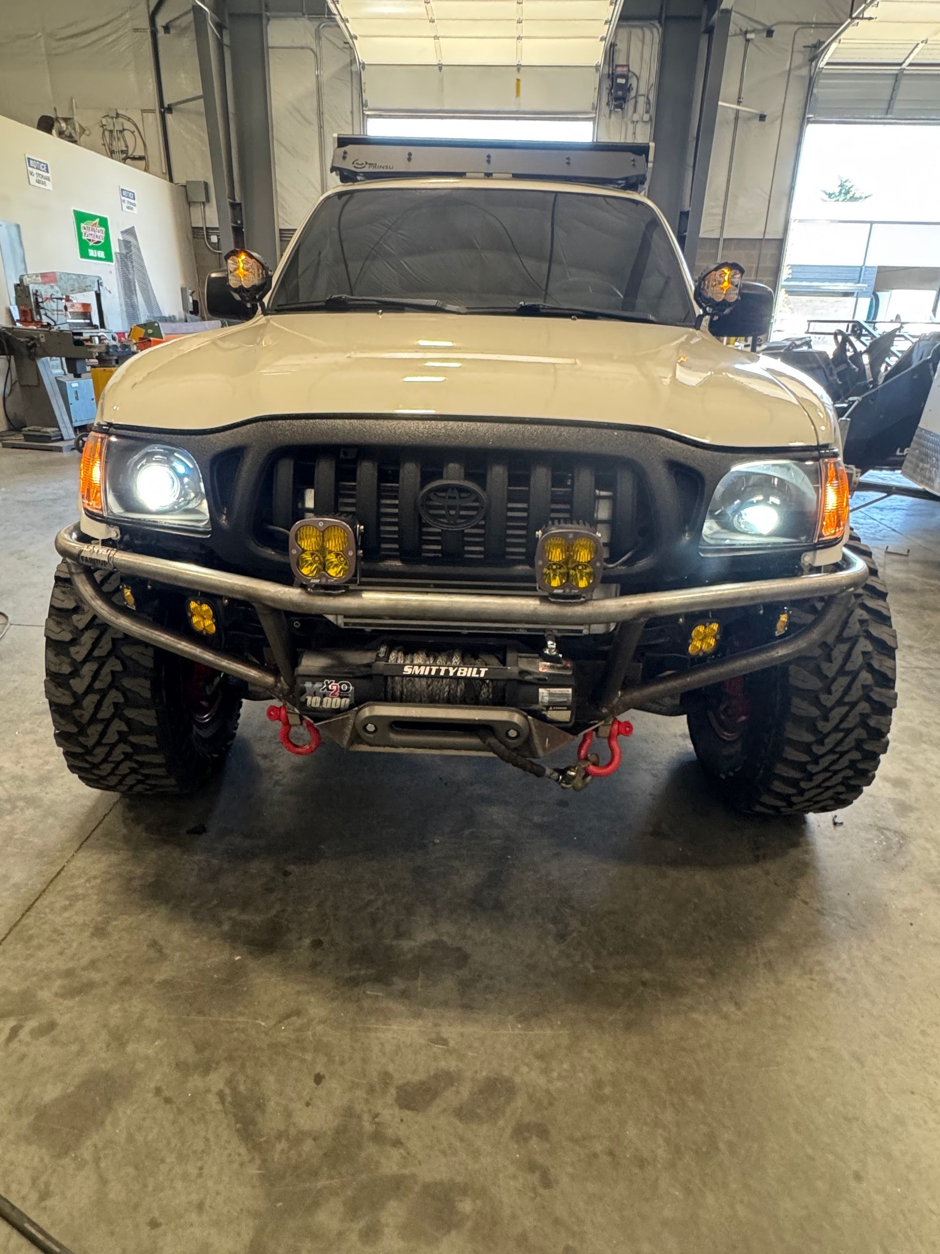 A toyota tacoma with a bumper and lights is parked in a garage.