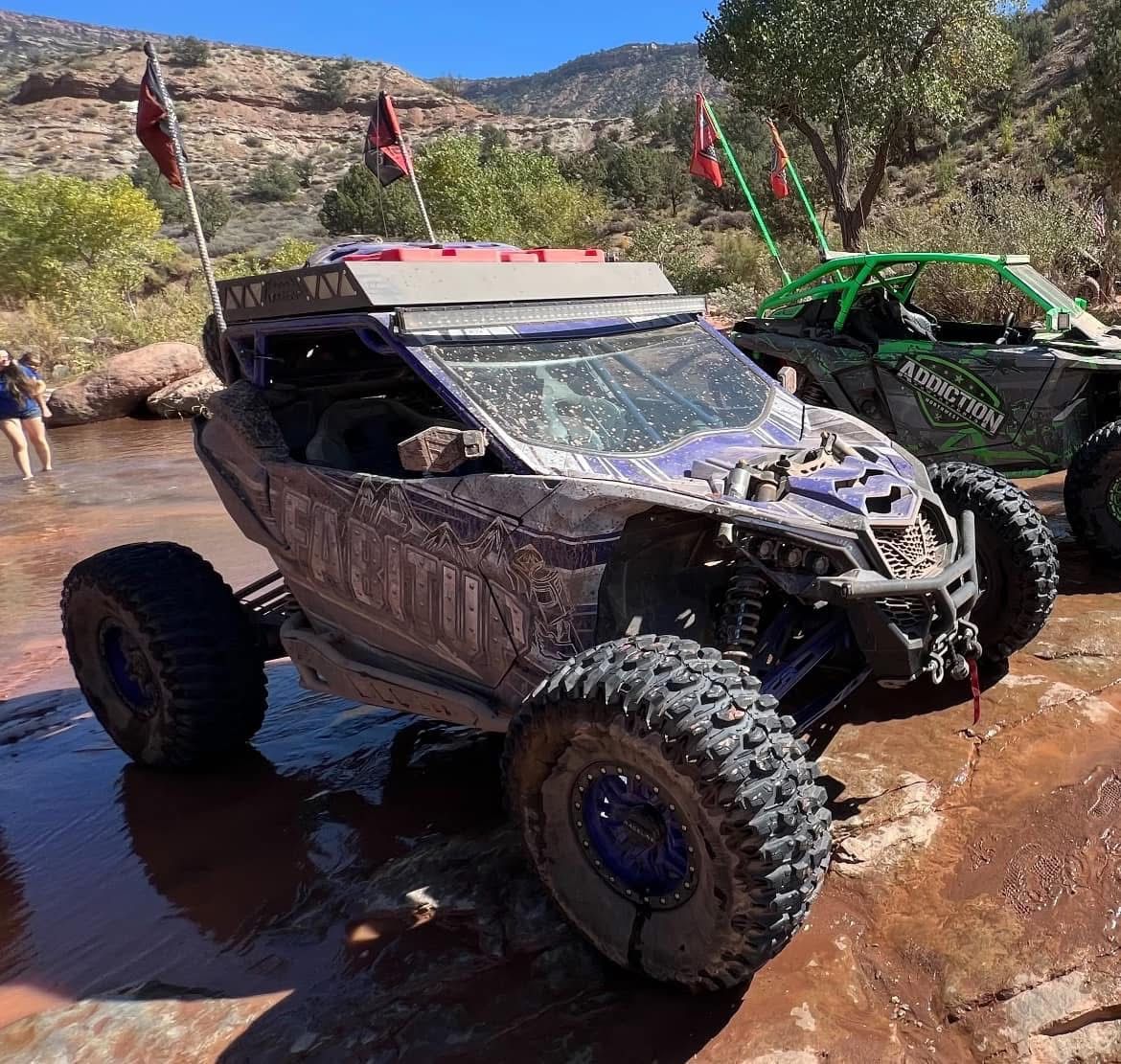 A purple atv is parked next to a green atv.