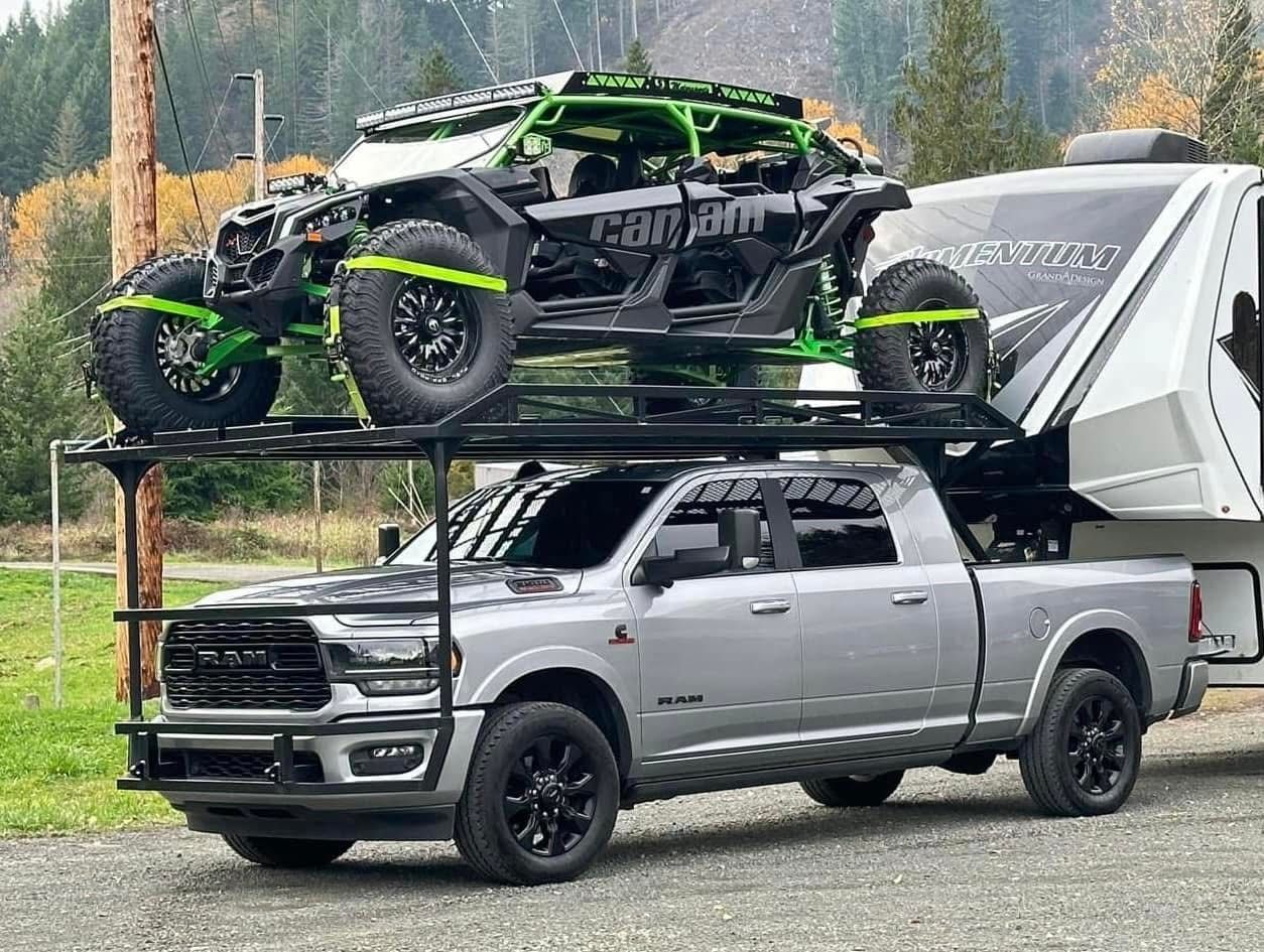 A truck is towing a trailer with two atvs on top of it.