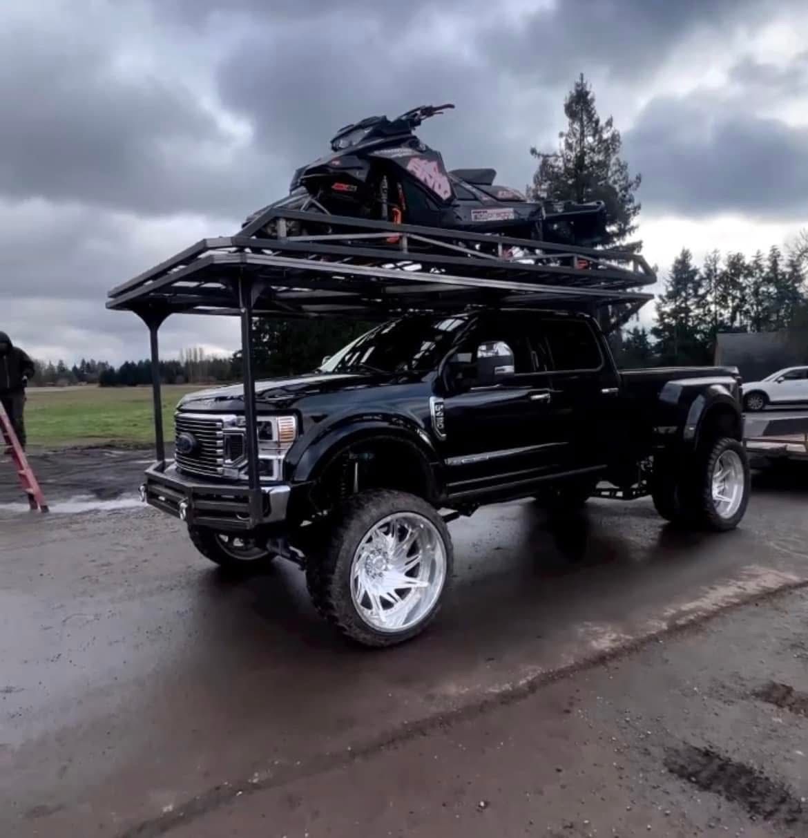 A black truck with a snowmobile on top of it