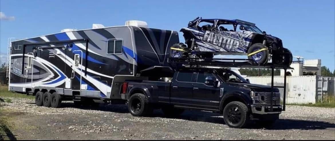 A truck is towing a trailer with a atv on top of it.