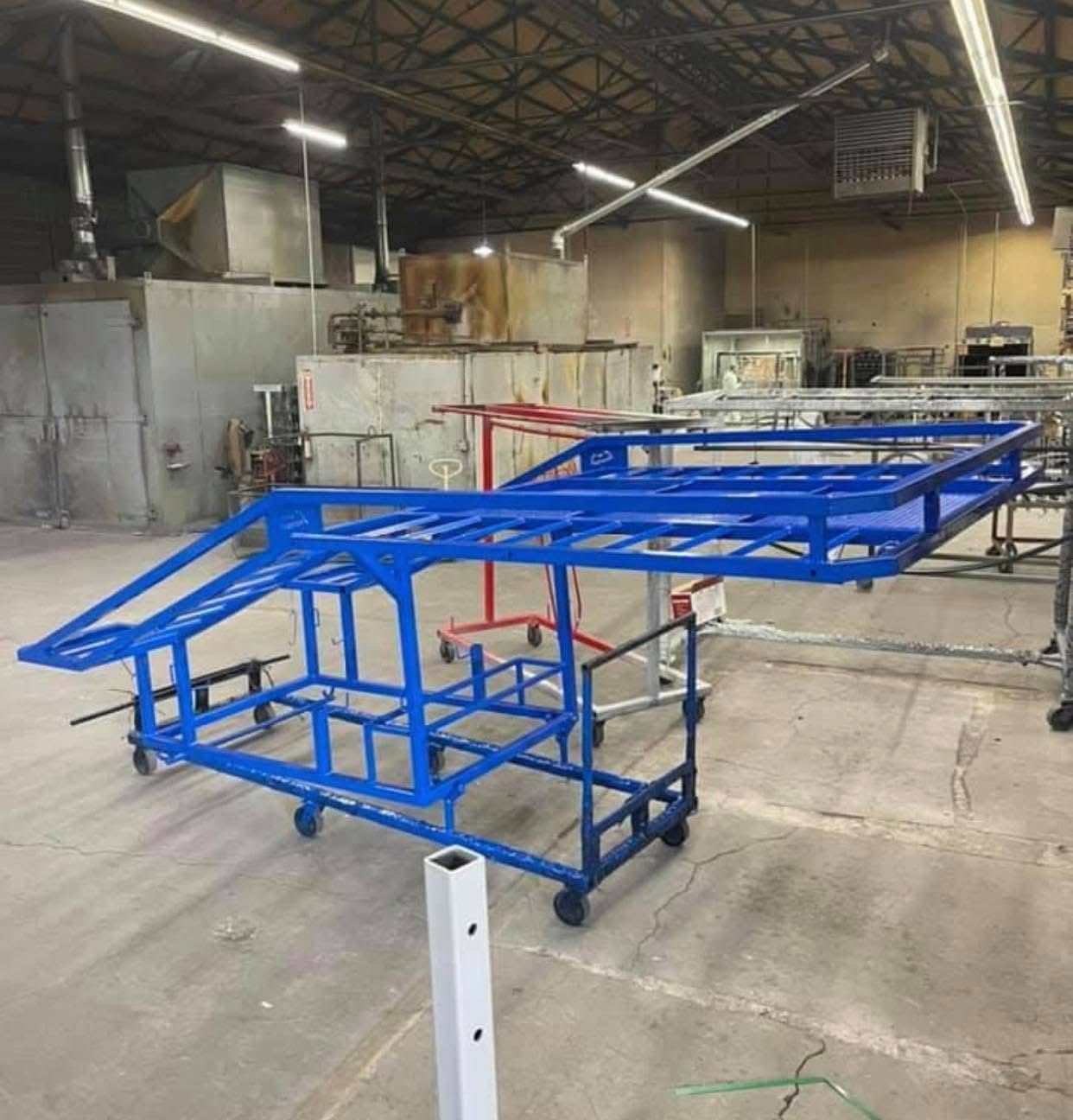 A blue metal structure with wheels is sitting in a warehouse.