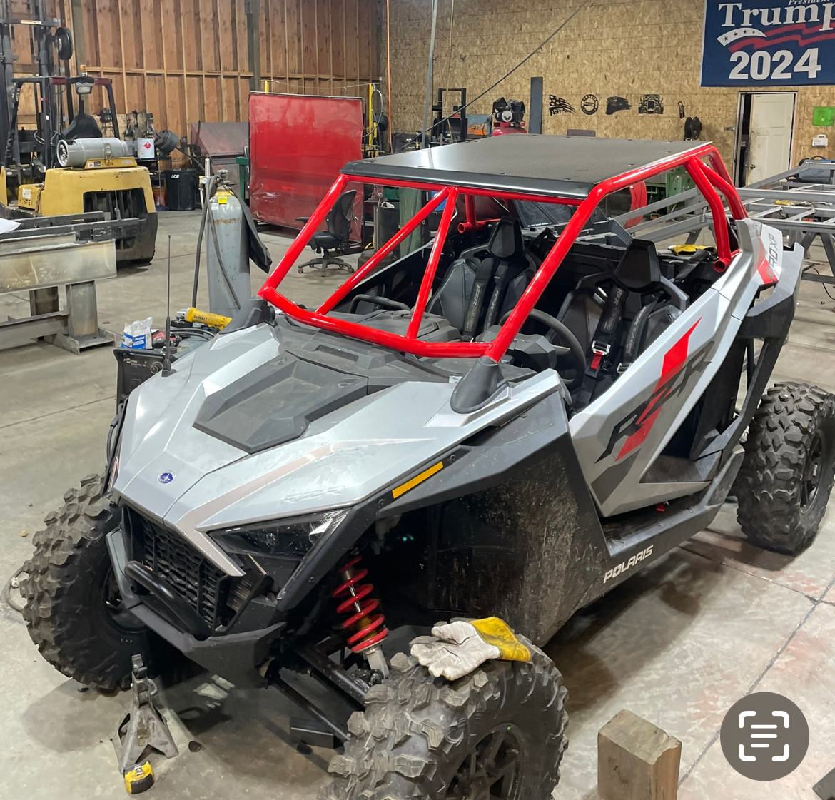 A UTV with a red cage parked in a shop.