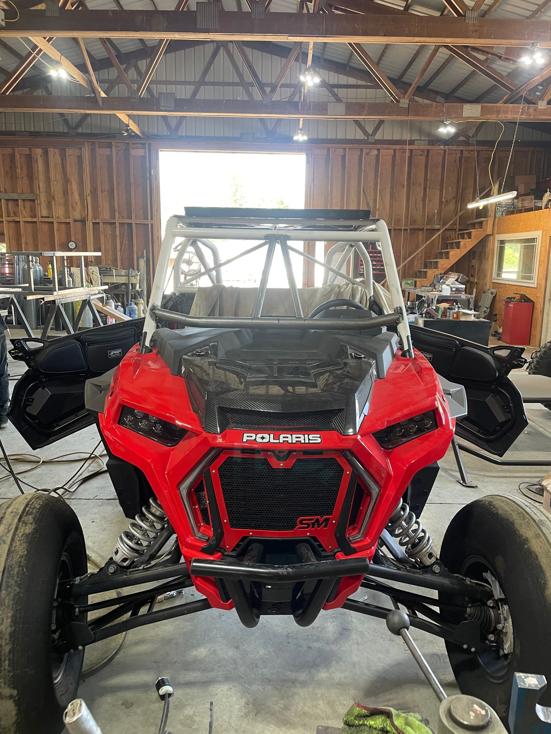 A red atv is parked in a garage with its doors open.