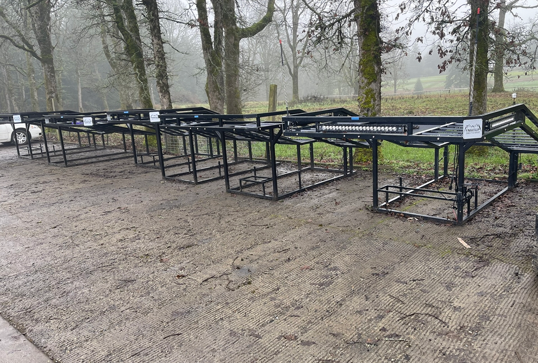 A row of metal crates are sitting on top of a dirt field.