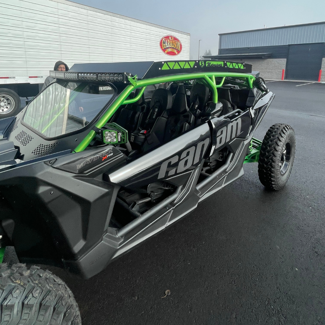 A black and green can am buggy is parked in a parking lot.