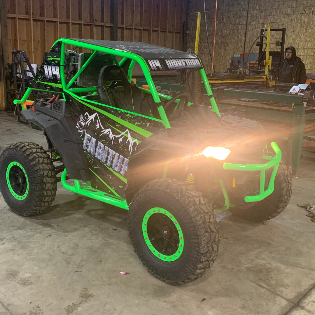 A green and black atv is parked in a garage.