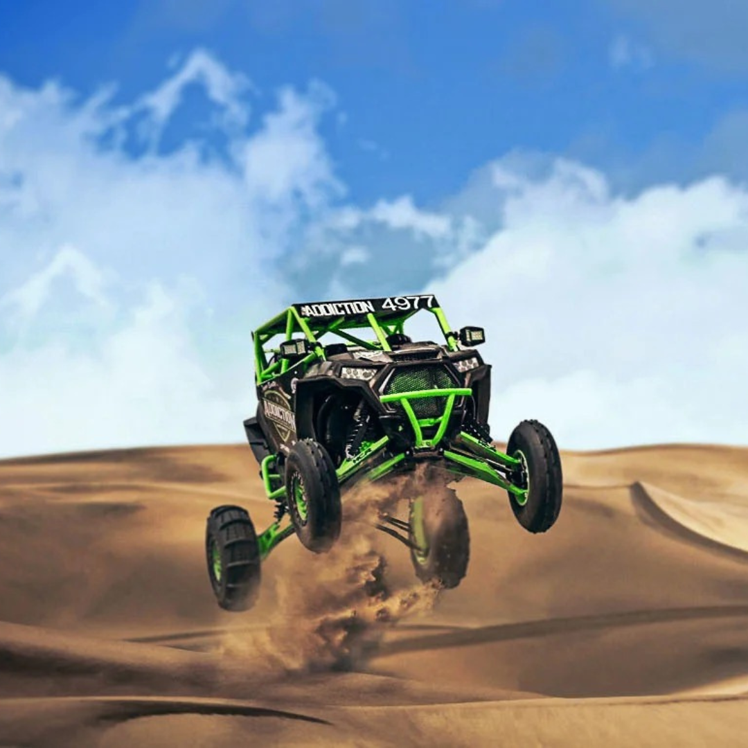 A green atv is flying through the air in the desert.