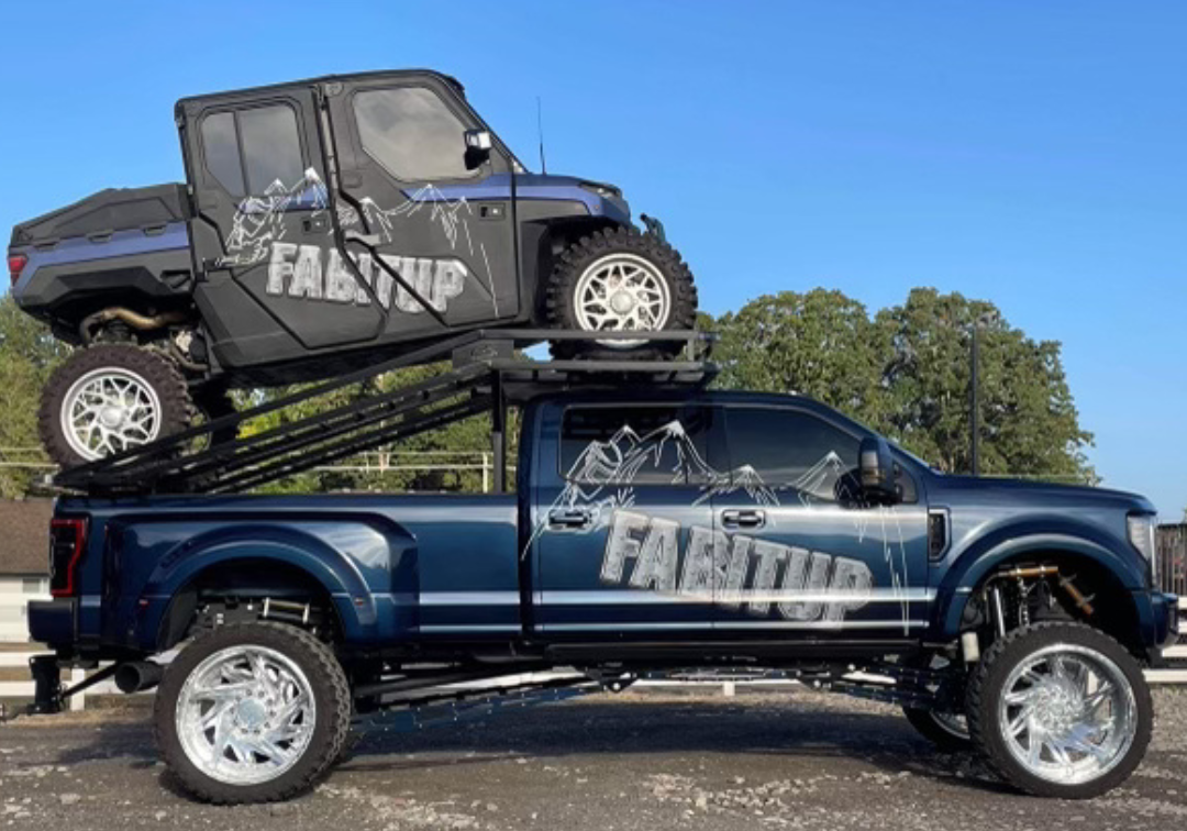A blue truck with a polaris rzr on top of it.