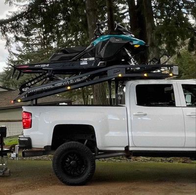 A white truck with a snowmobile on top of it.