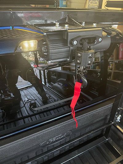 A close up of a winch in the back of a truck.