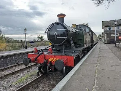 Steam train (4555) at a station platform, overcast sky.