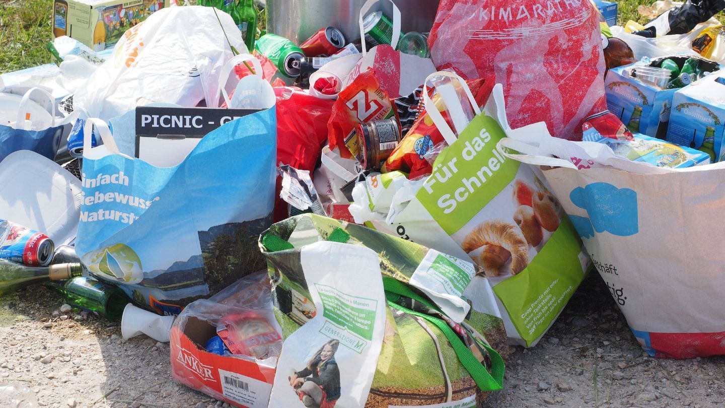 Pile of trash and discarded food packaging on the ground, outdoors.