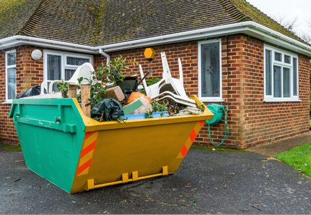 Green and yellow dumpster filled with trash sits in front of a brick house.