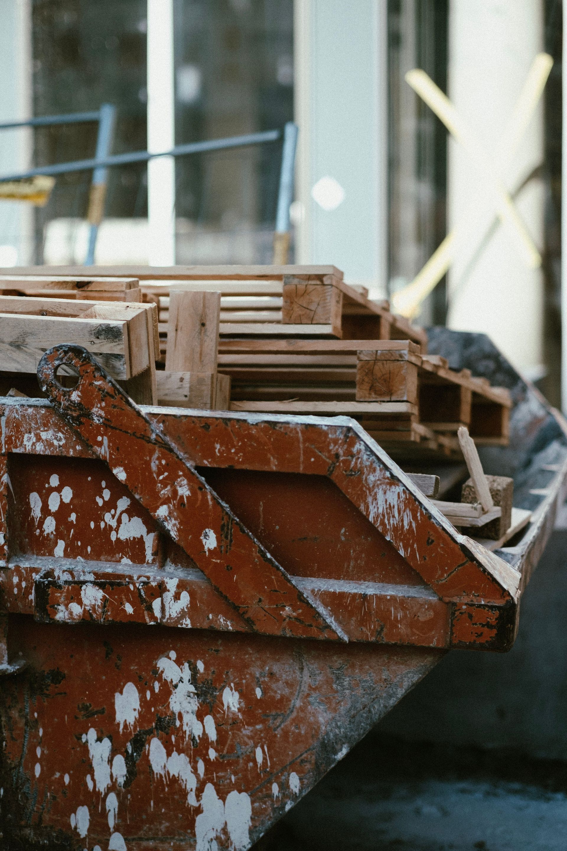 Rusty metal dumpster filled with wooden crates in an industrial setting