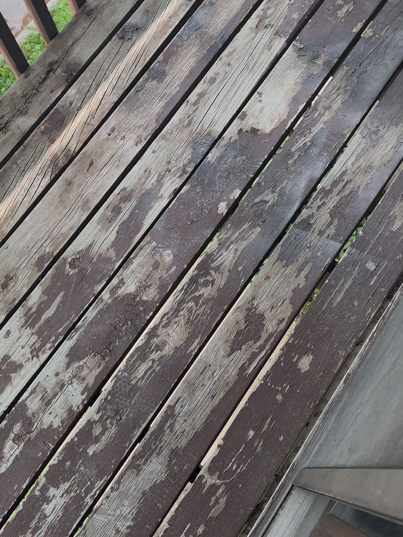 Weathered wooden deck planks, painted brown, with peeling paint.