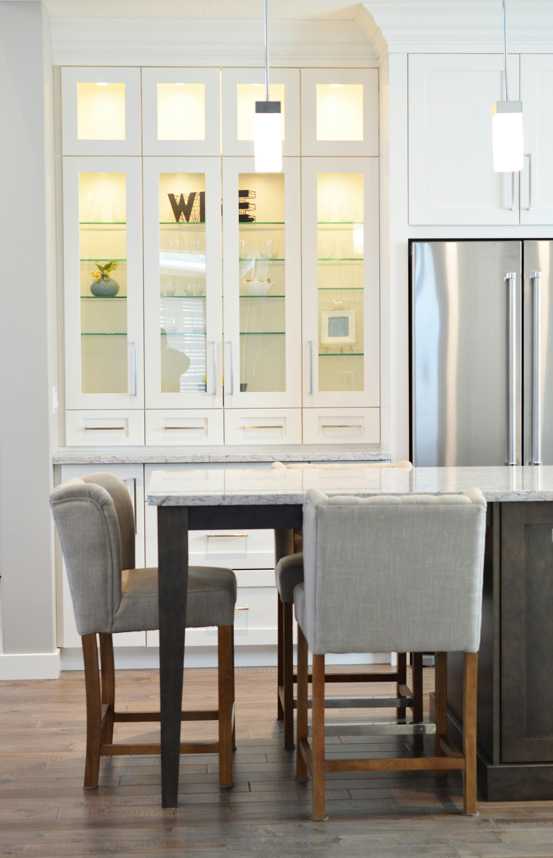Kitchen with light-colored cabinets, a stainless steel refrigerator, and a dark island with two bar stools.