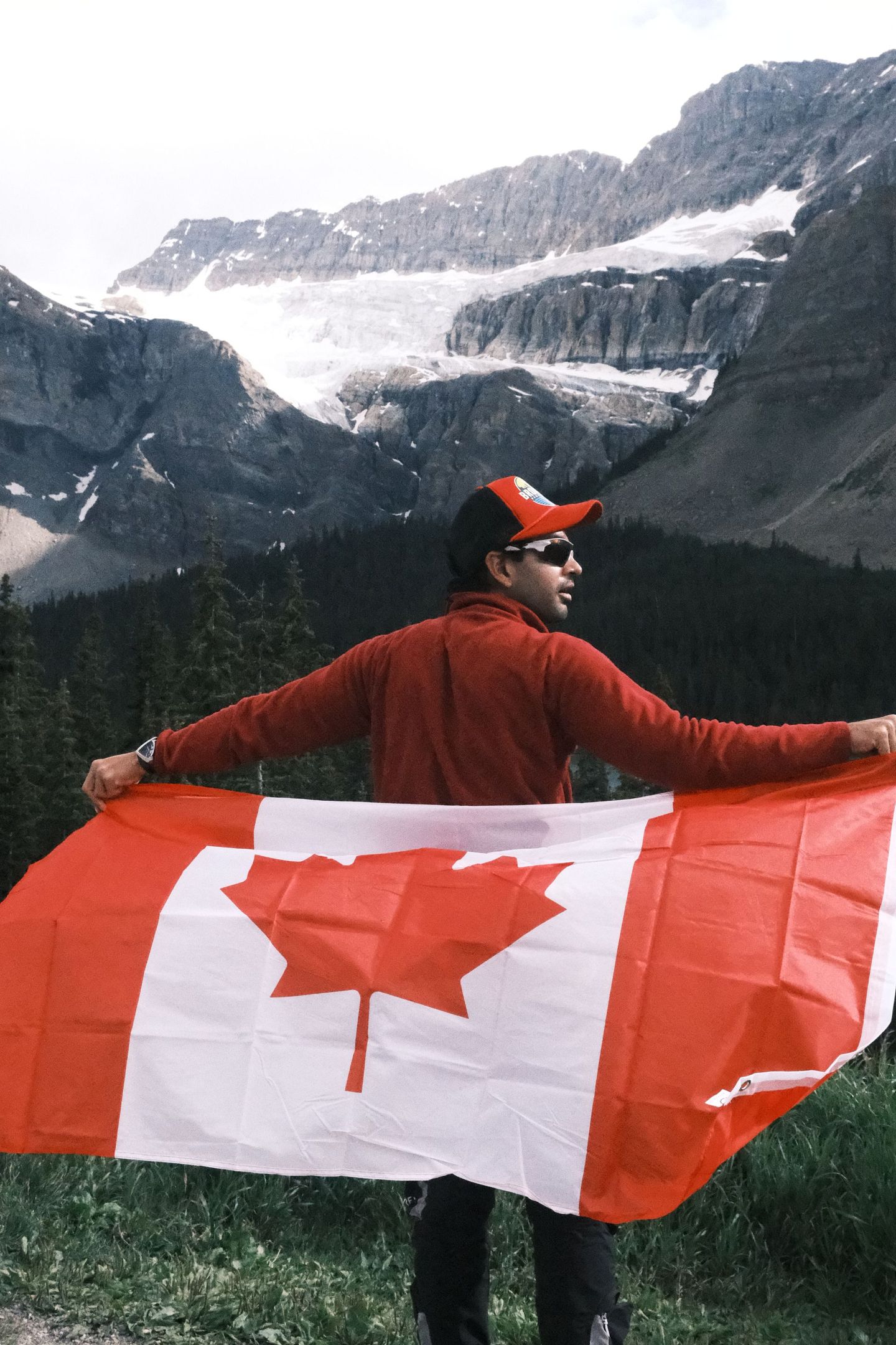 Guest celebrating with Canadian flag at Crowfoot Glacier on Icefield Parkway, Banff Bear Travel day tour from Calgary