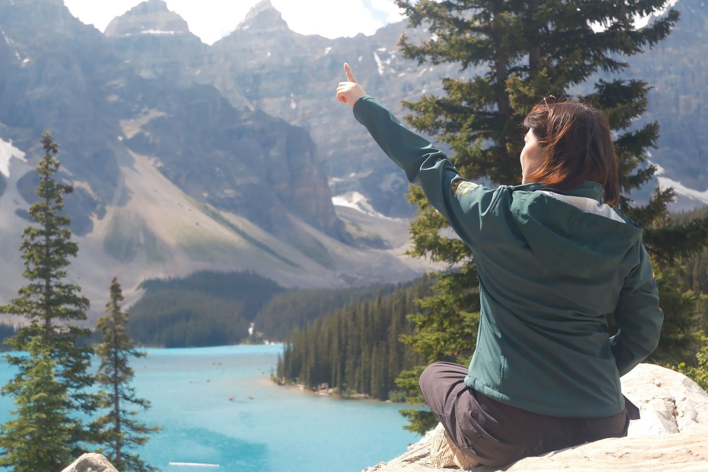 Guest at Moraine Lake Rockpile with Valley of the Ten Peaks and turquoise lake in background, Banff Bear Travel summer tour
