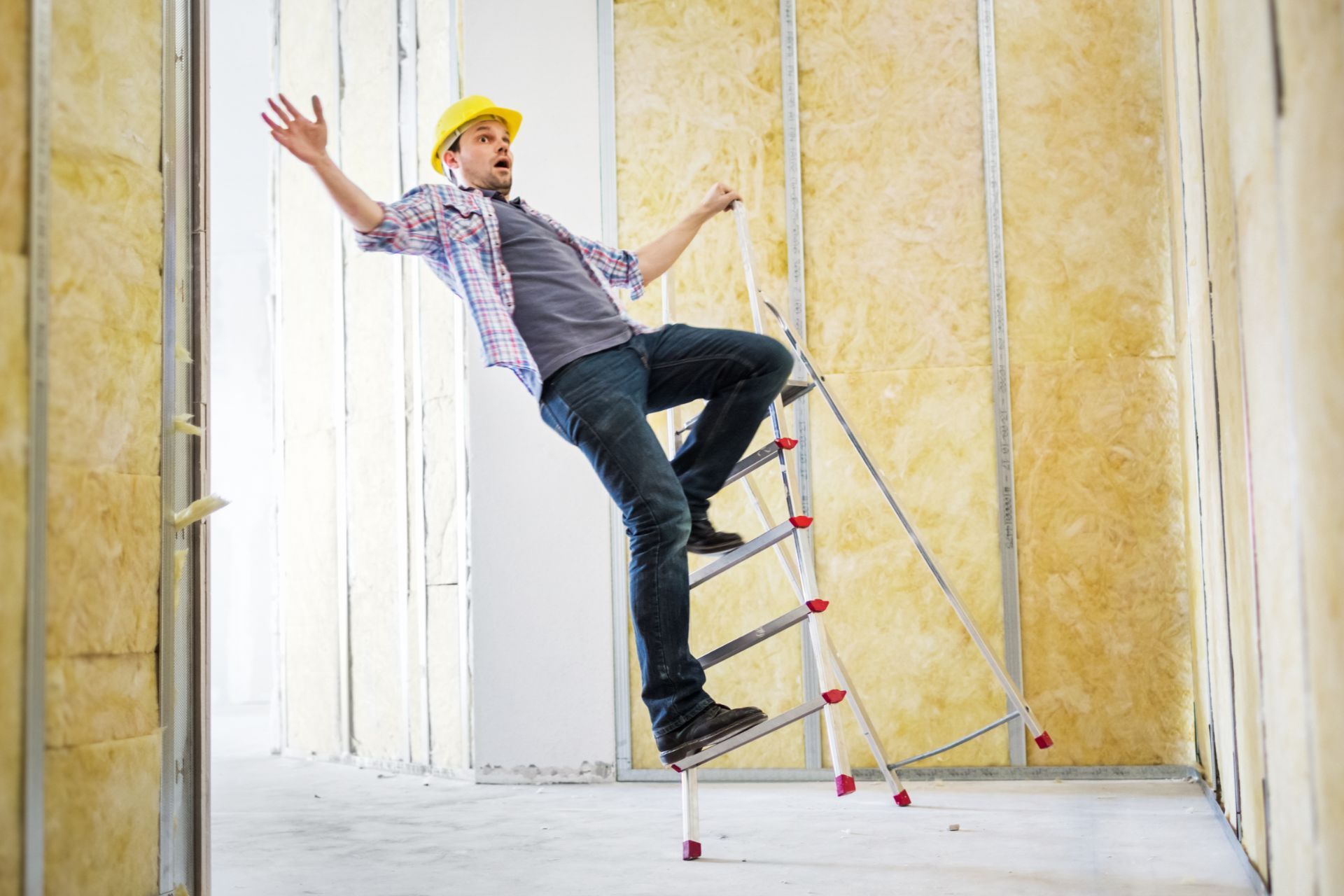 A man is falling off a ladder in a room.