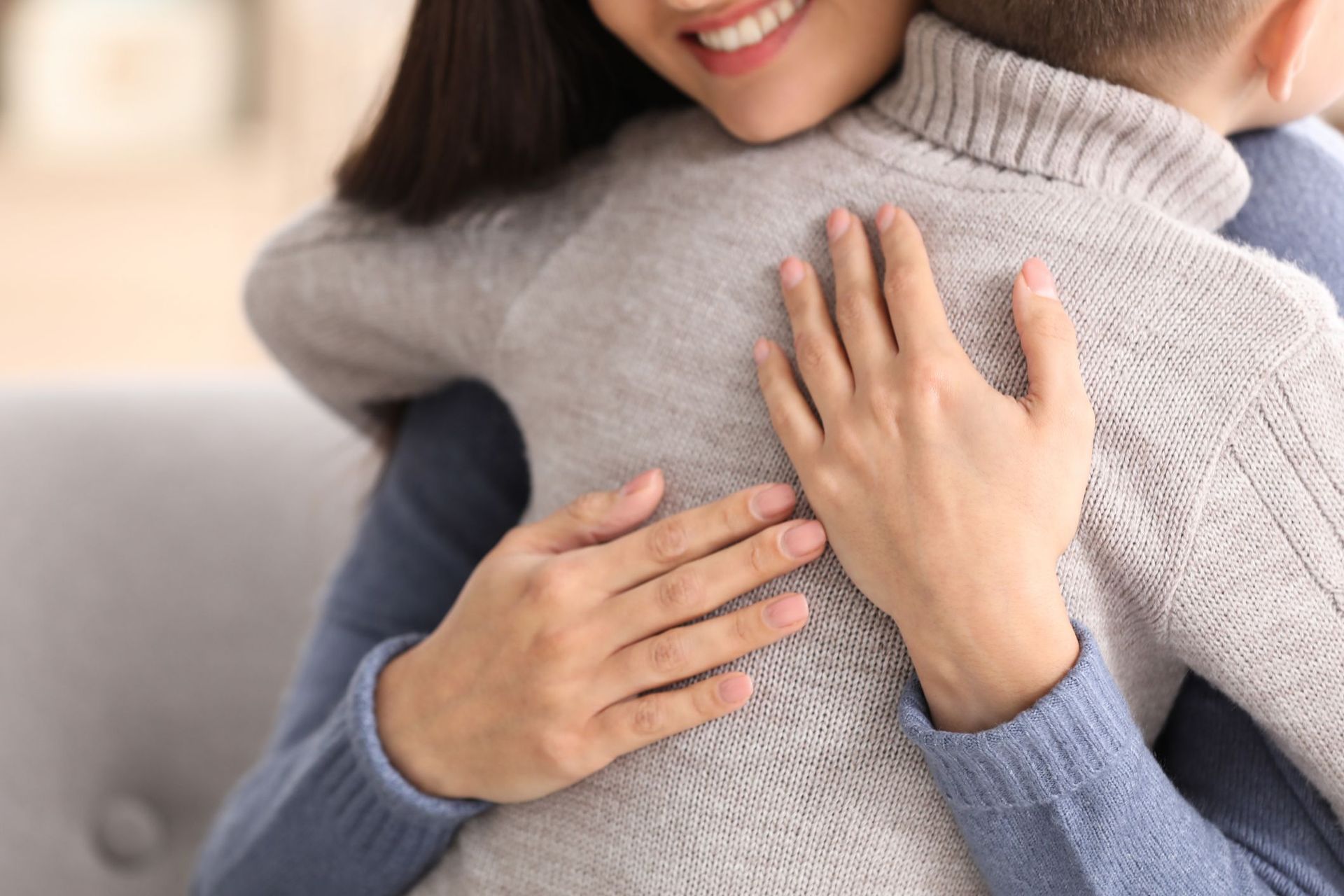A woman is hugging a man on a couch.