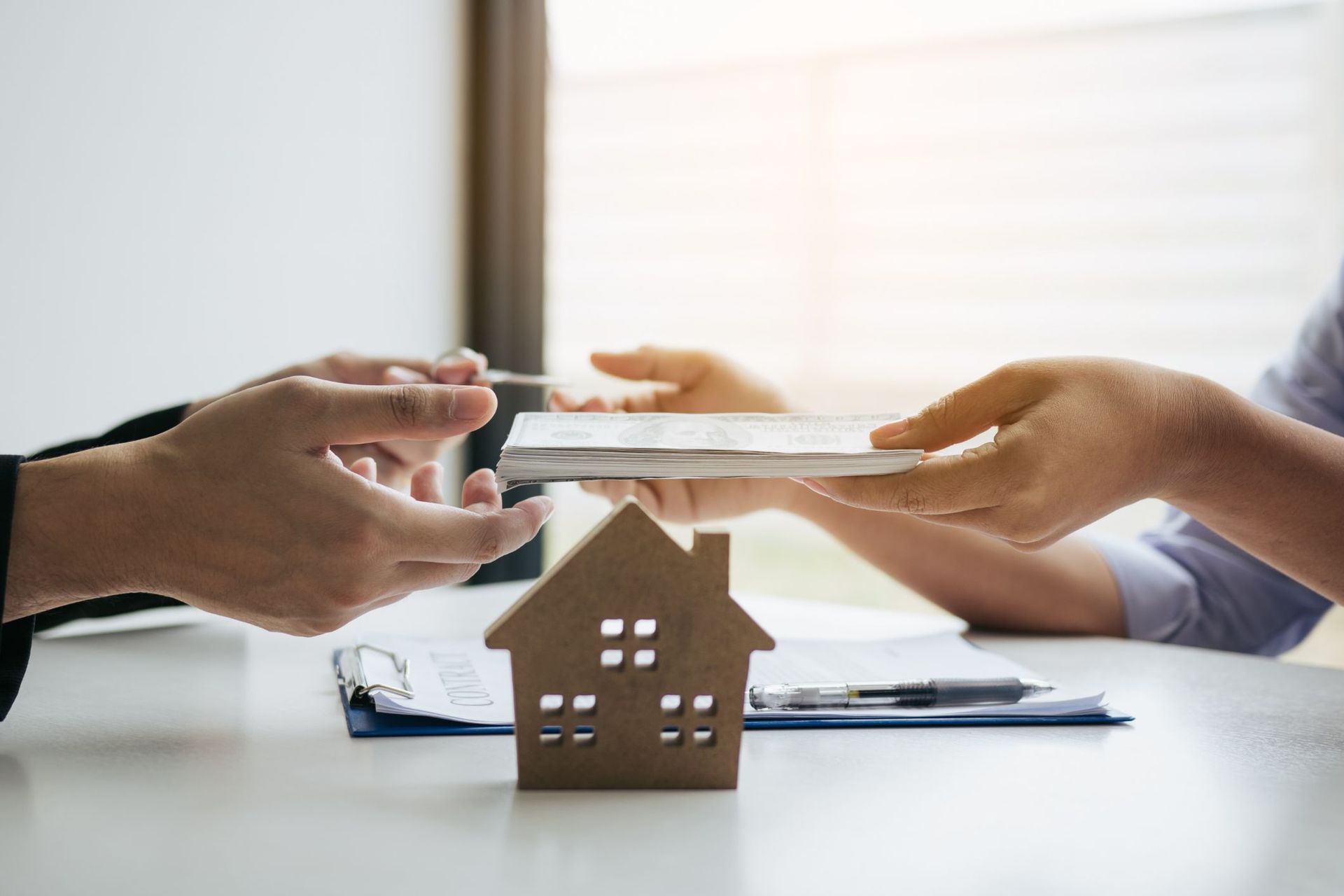 A person is holding a piece of paper in front of a model house.