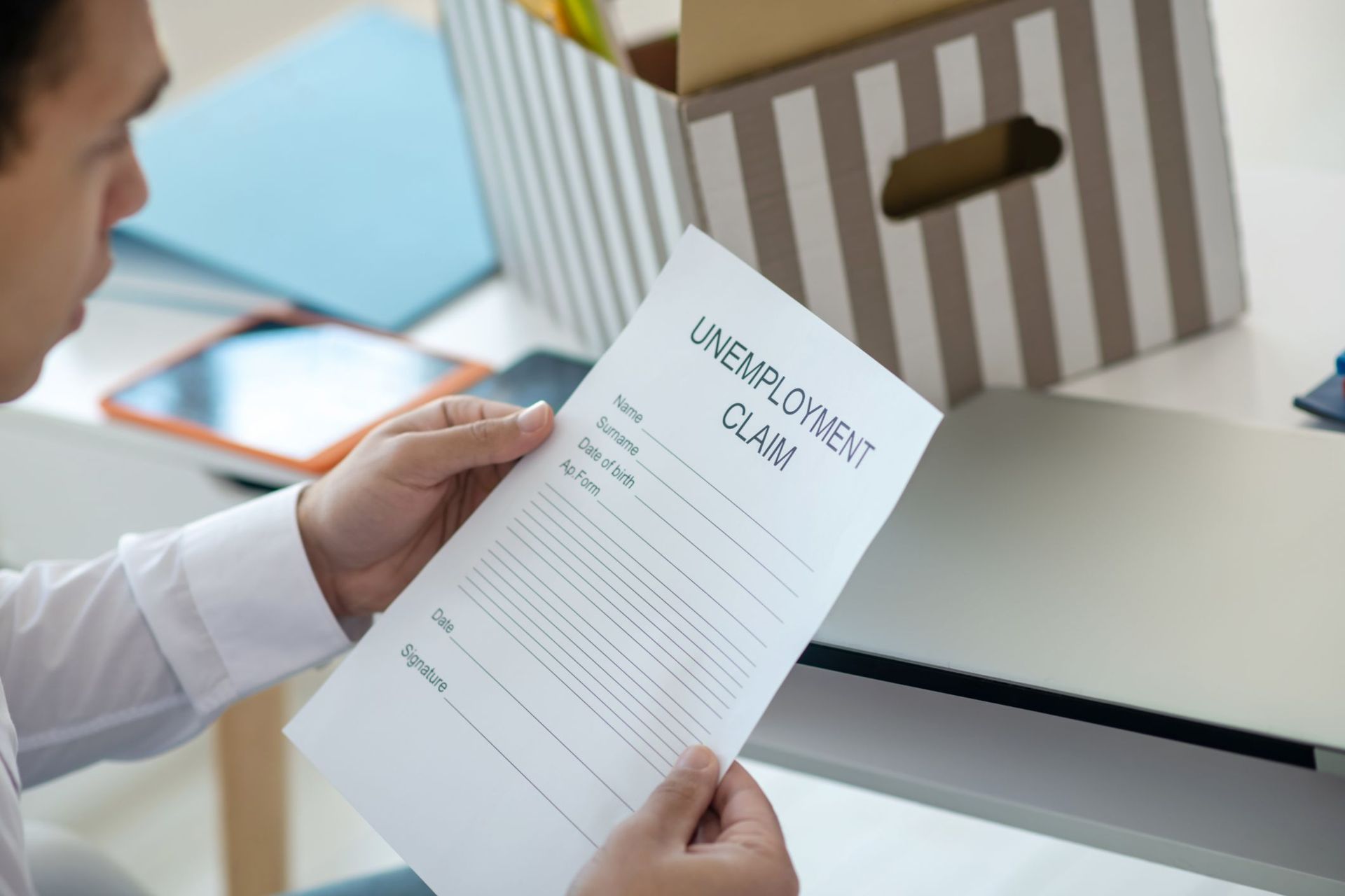 A man is holding a piece of paper that says `` unemployment claim ''.