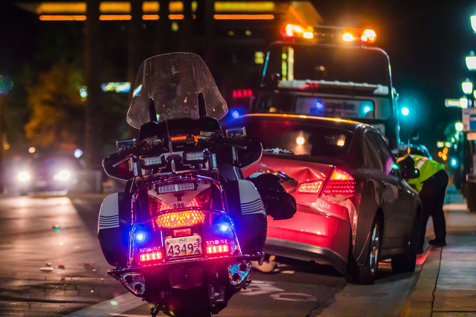 A police motorcycle is parked next to a car that has been damaged in an accident.