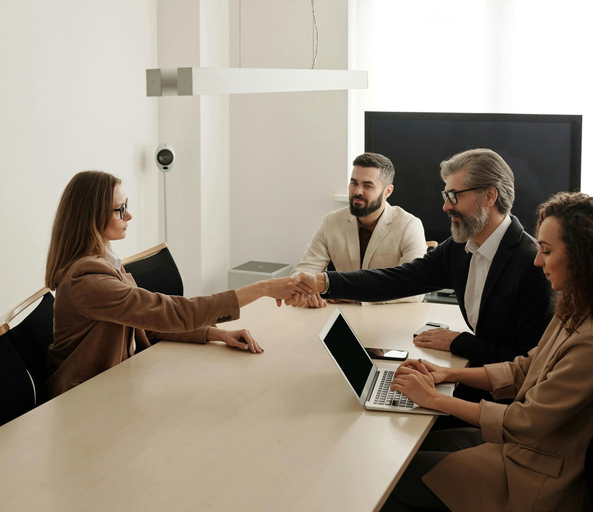 A group of people are sitting around a table shaking hands.