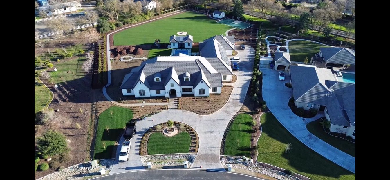 An aerial view of a large house with a large driveway leading to it.