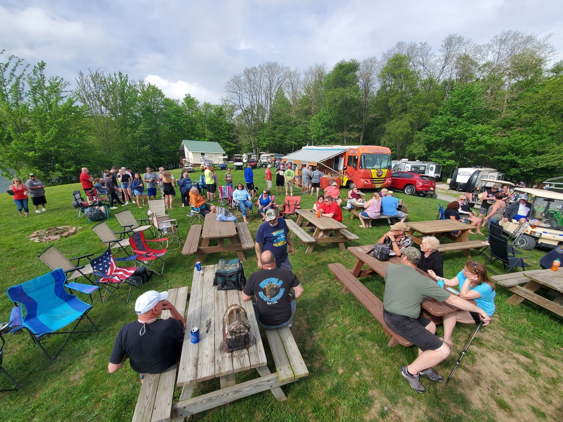 a group of people are sitting at picnic tables in a field .