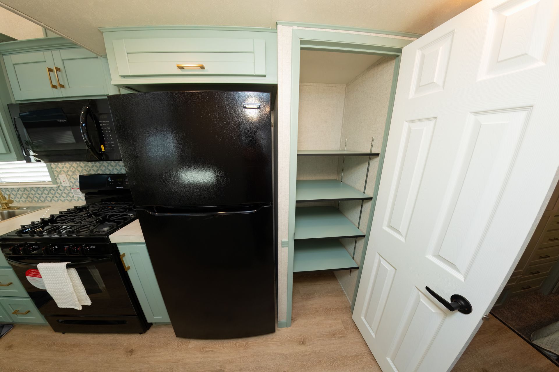 a kitchen with a black refrigerator and a white door
