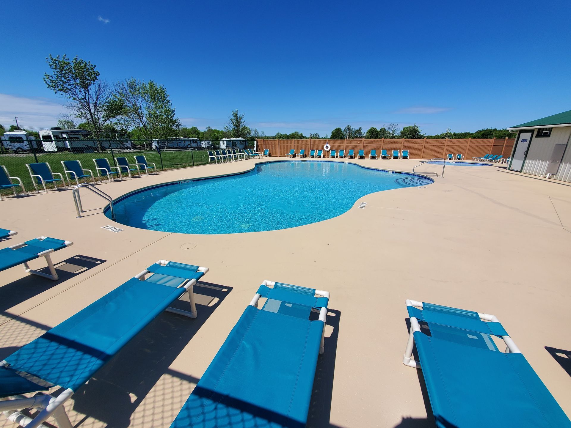 a large swimming pool surrounded by blue lounge chairs on a sunny day .