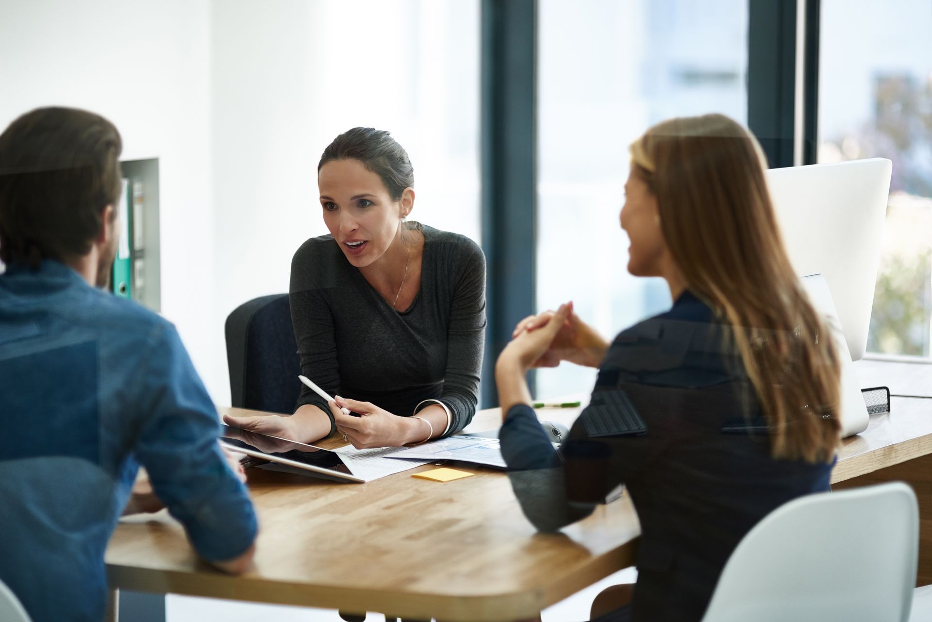 Three people sitting at desk with paperwork on the desk